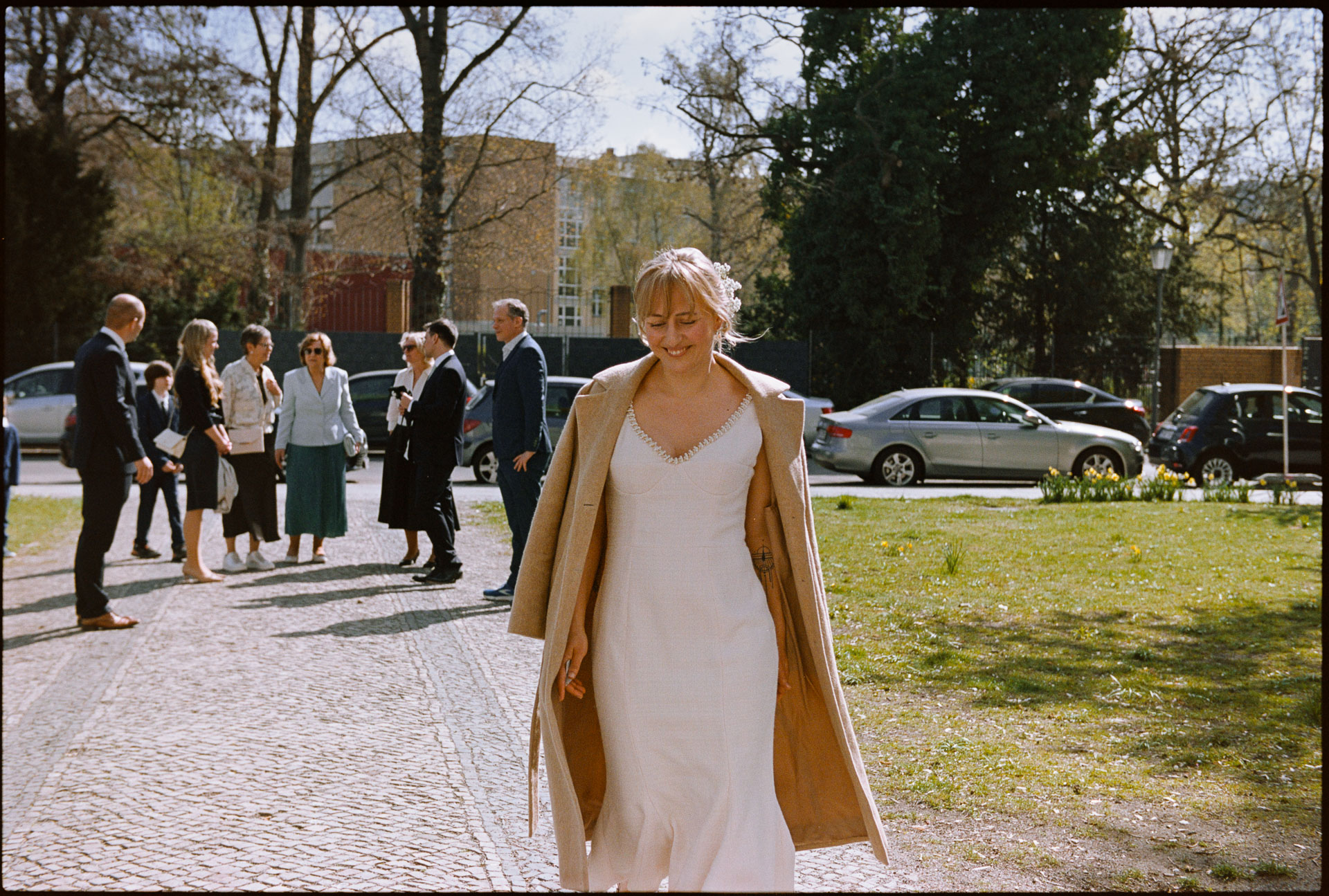 The bride walking outdoors, guests behind, Irena & Peter wedding in Berlin