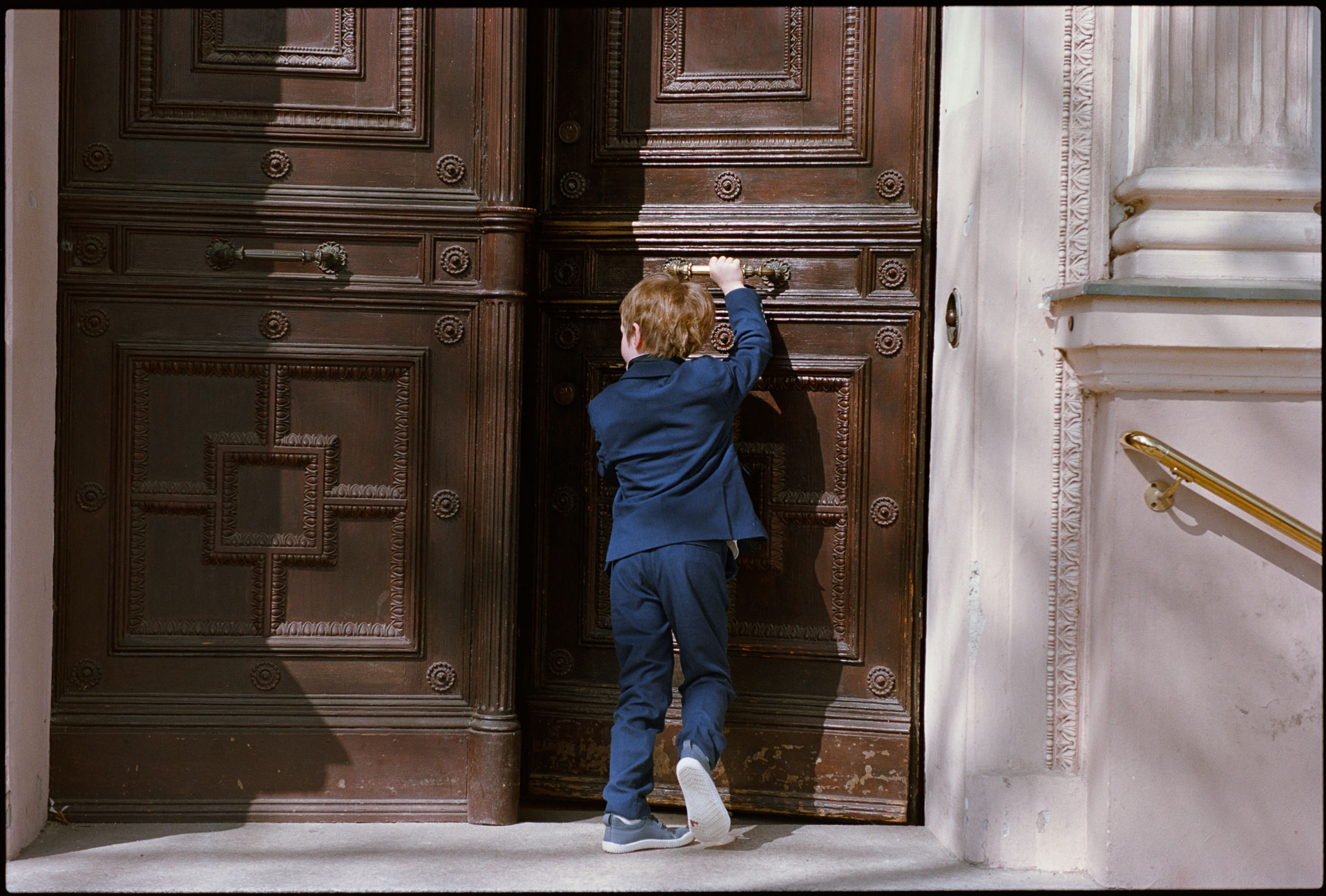 A child pushing open a large wooden door, Irena & Peter wedding in Berlin