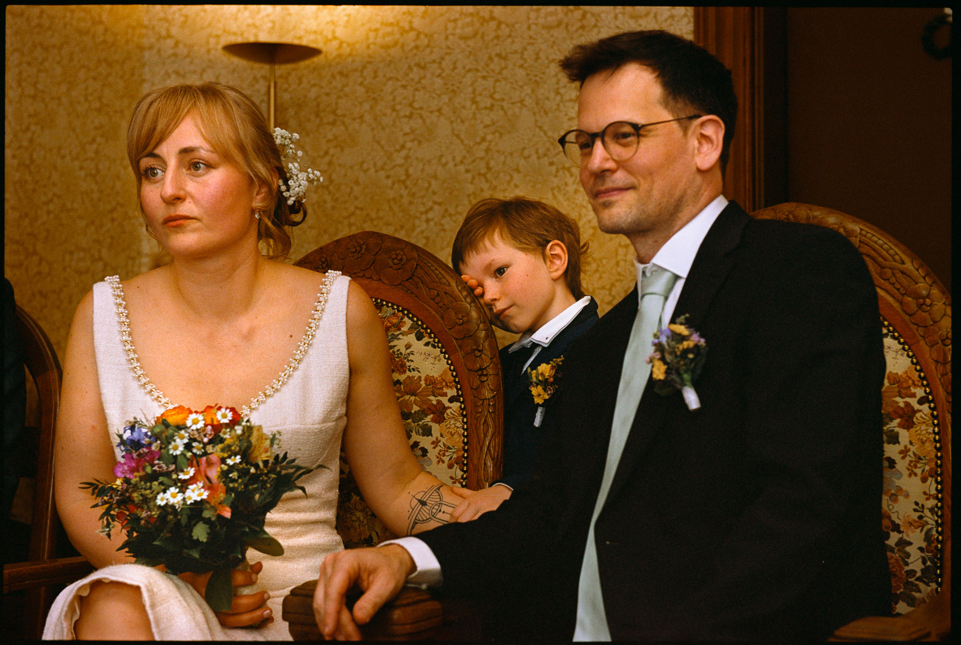 The couple seated with a child at the ceremony, Irena & Peter wedding in Berlin