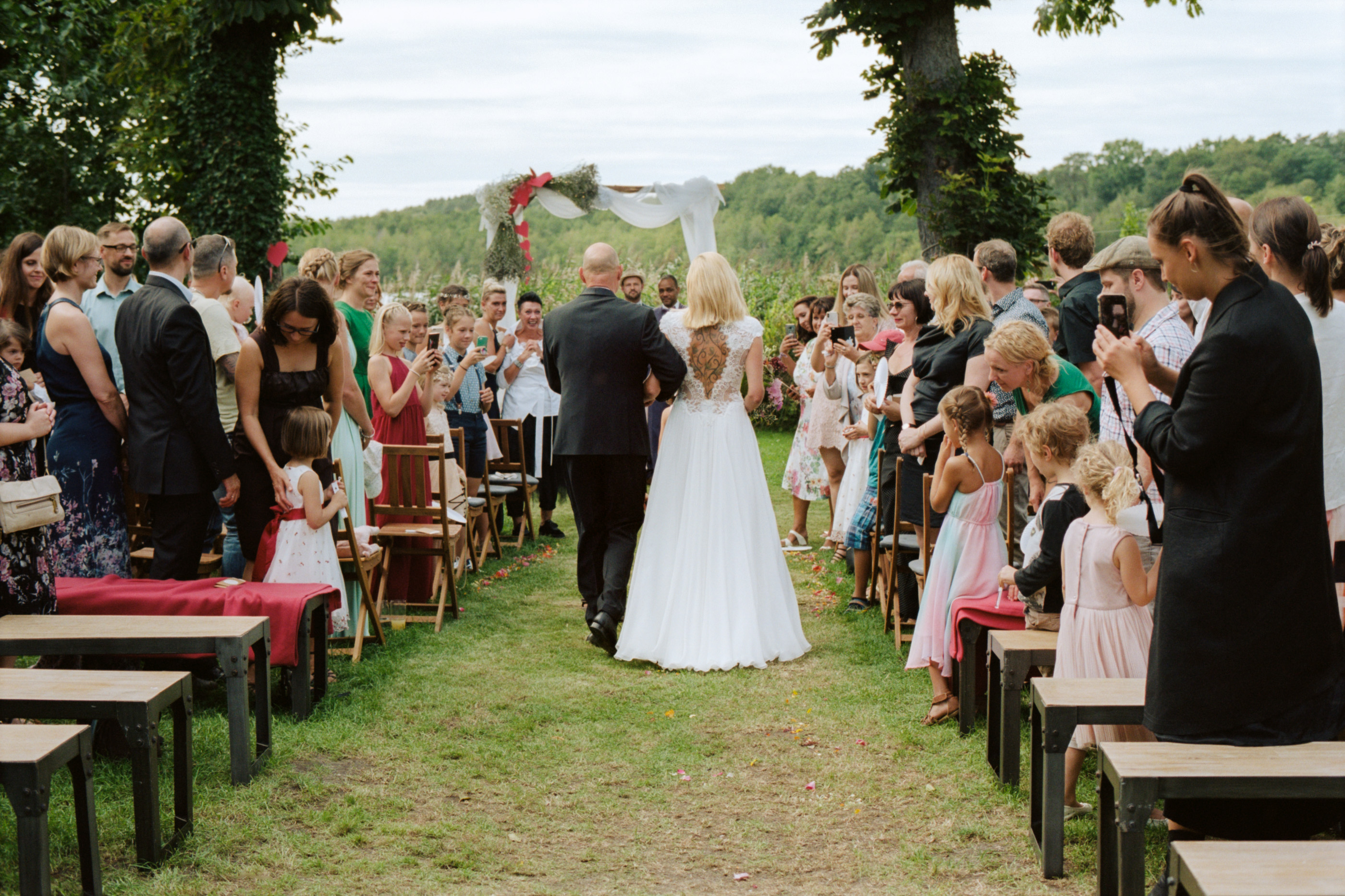 The wide garden aisle lined with guests before the lake, Linda & Thomas wedding in Berlin