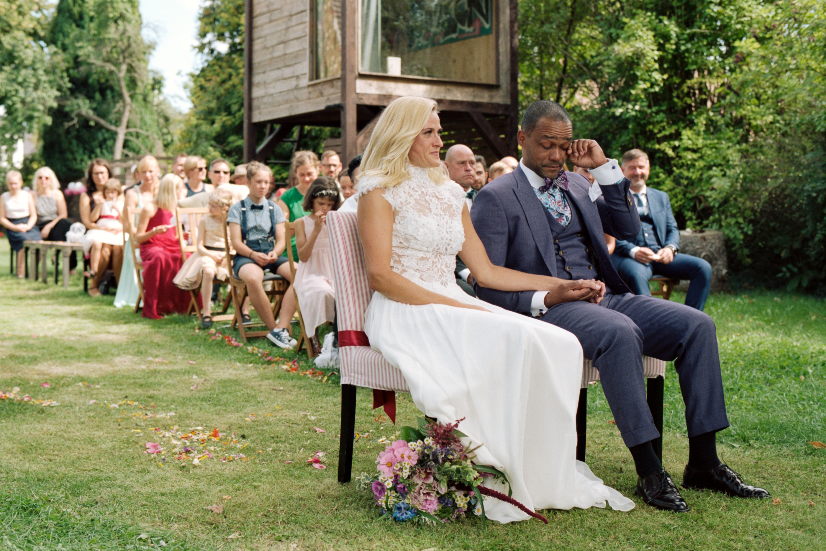 The couple seated together during the outdoor garden ceremony, Linda & Thomas wedding in Berlin