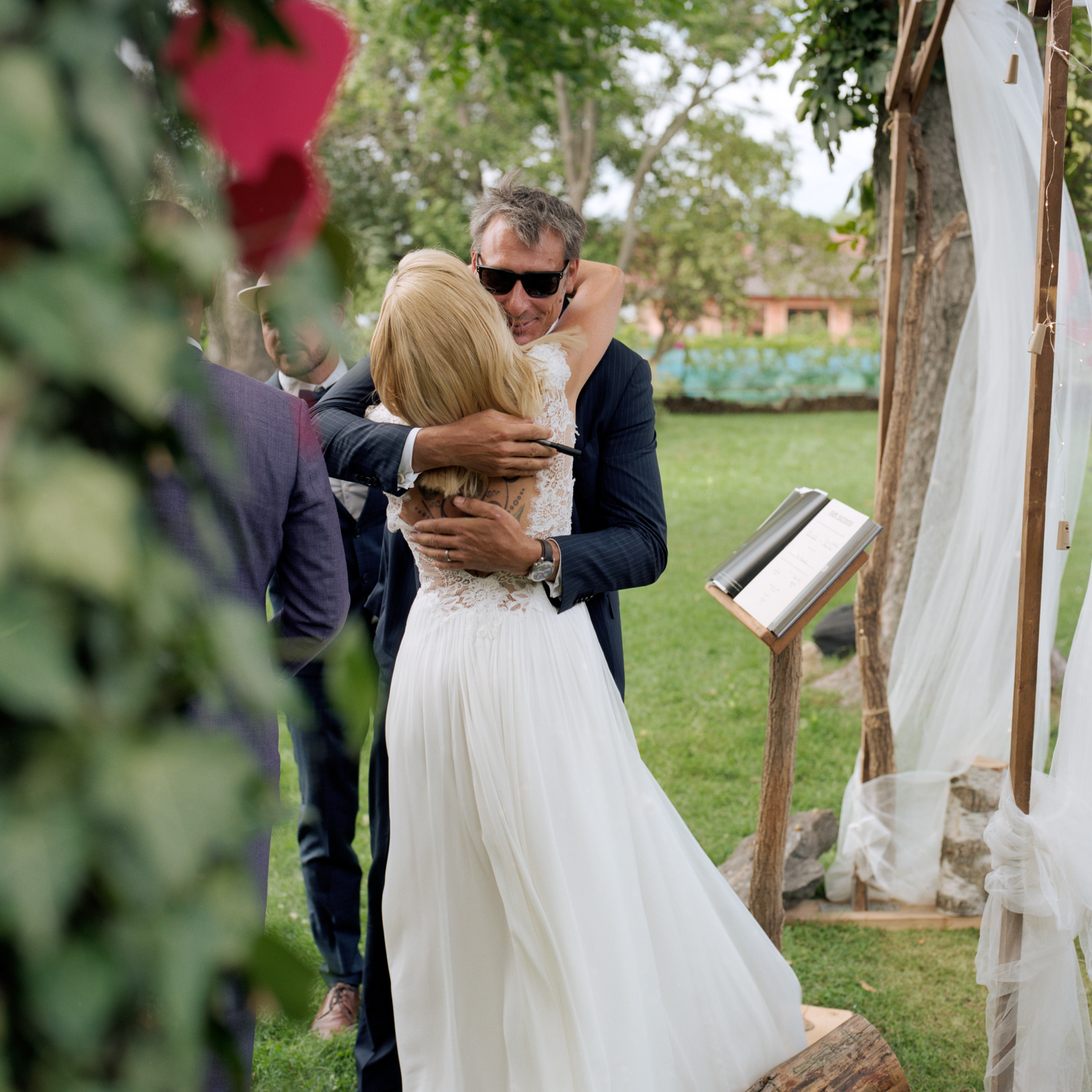 The bride embracing a guest beside the flower-covered arch, Linda & Thomas wedding in Berlin