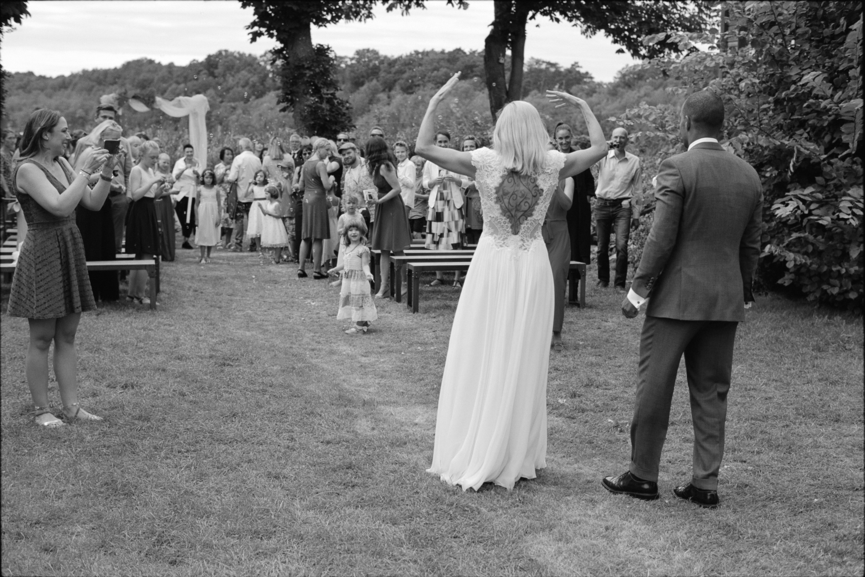 The newlyweds walking back down the aisle as guests celebrate, black and white, Linda & Thomas wedding in Berlin