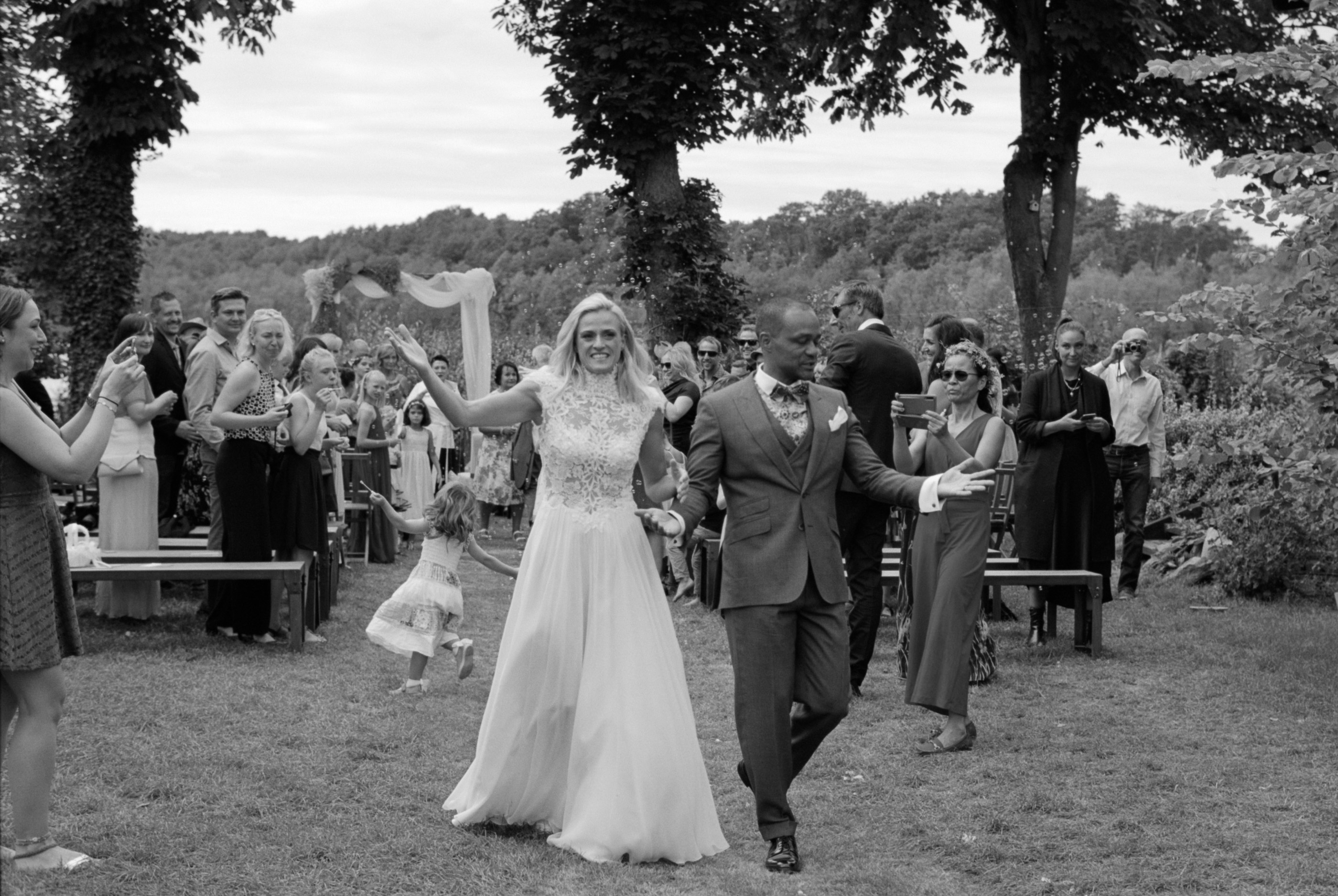 The couple walking through the garden with their guests, black and white, Linda & Thomas wedding in Berlin