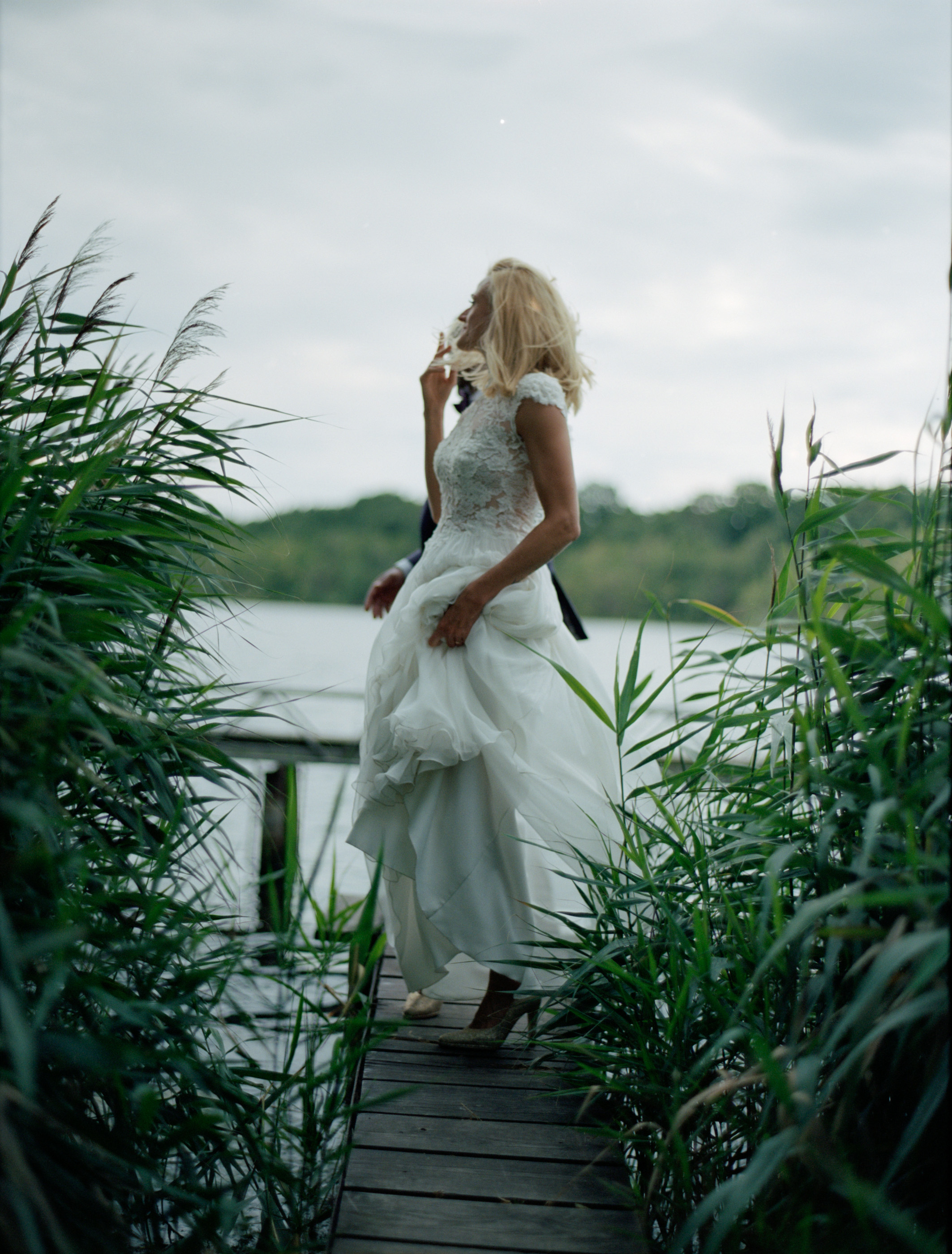 The bride at the water's edge among the reeds at dusk, Linda & Thomas wedding in Berlin