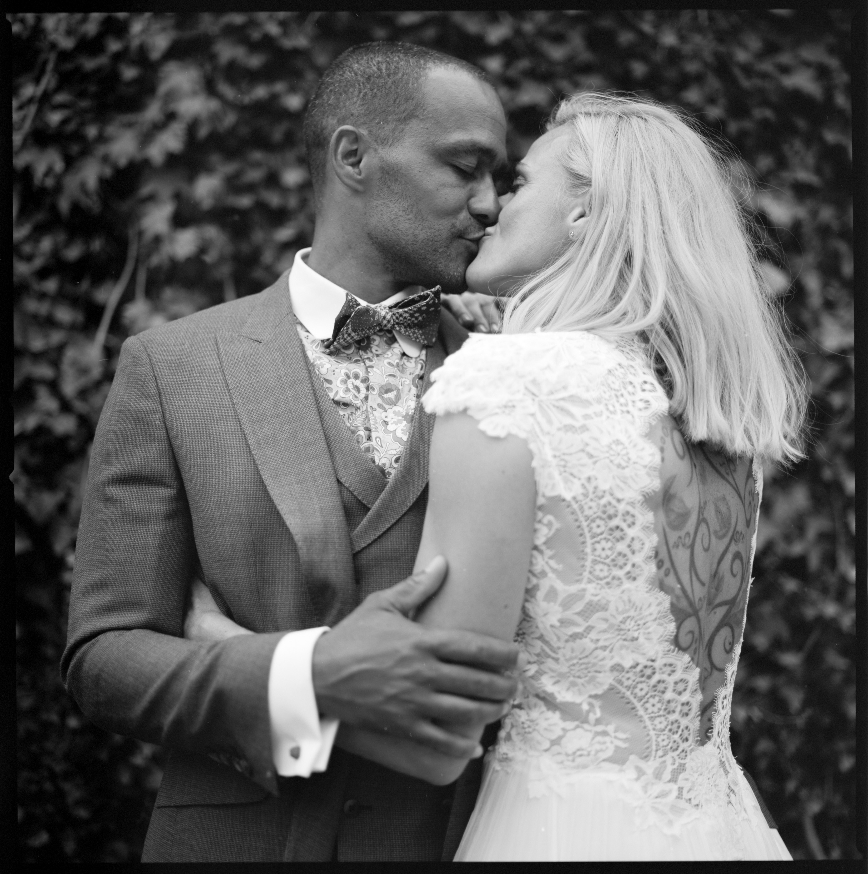 The couple in a close embrace among greenery, black and white, Linda & Thomas wedding in Berlin