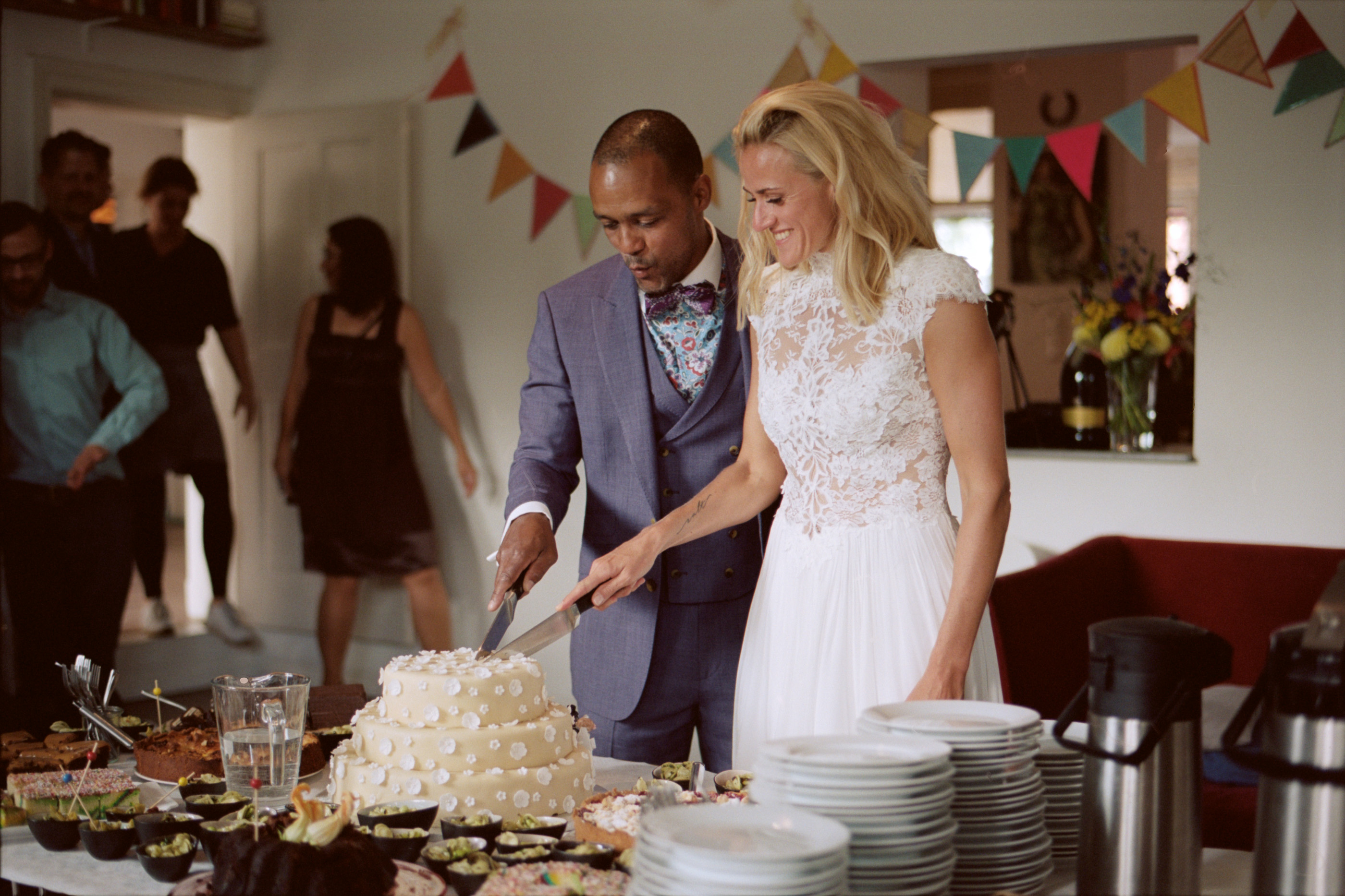 The couple cutting their cake beneath the bunting, Linda & Thomas wedding in Berlin