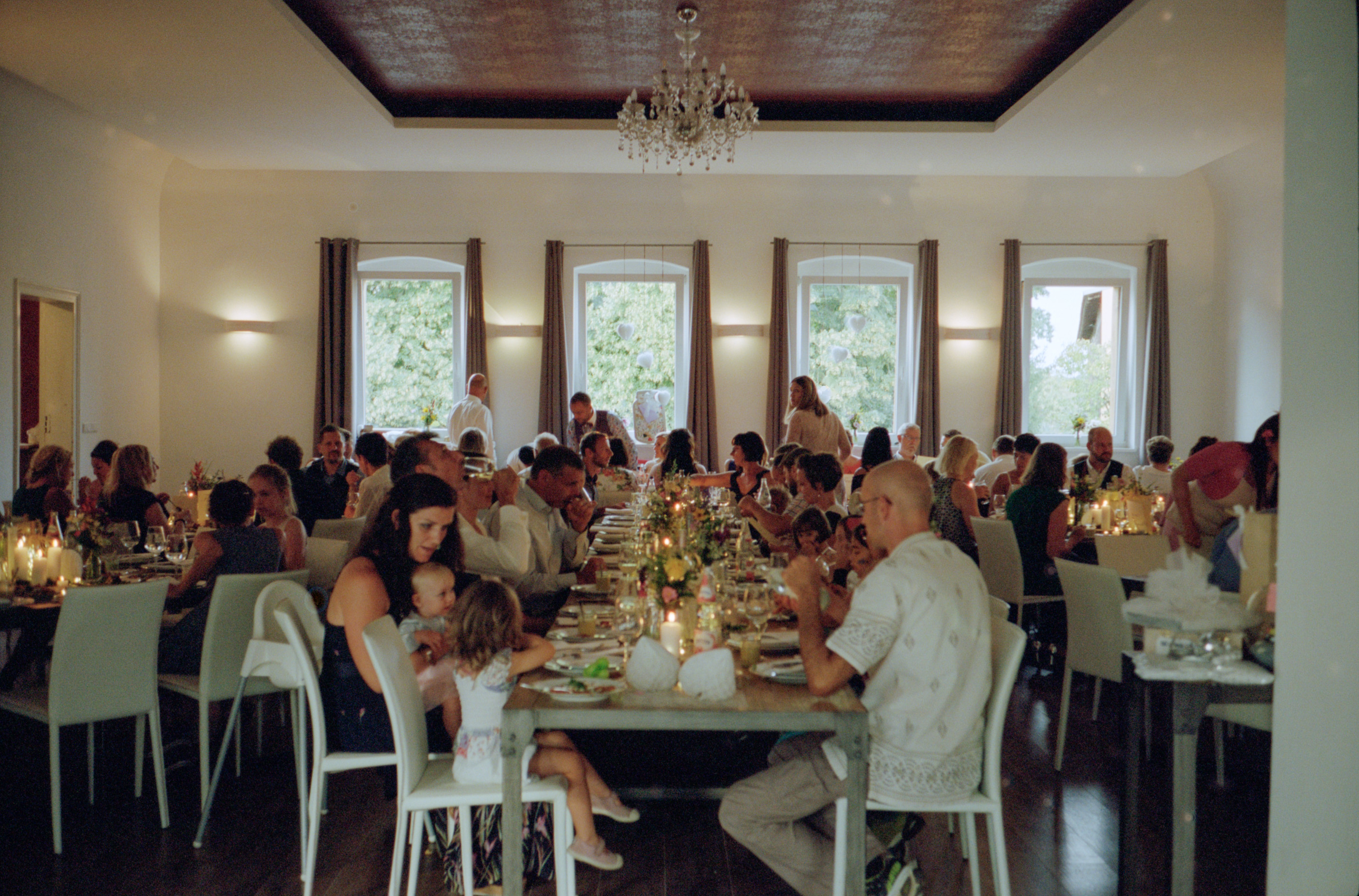 The reception hall set with long tables under a chandelier, Linda & Thomas wedding in Berlin