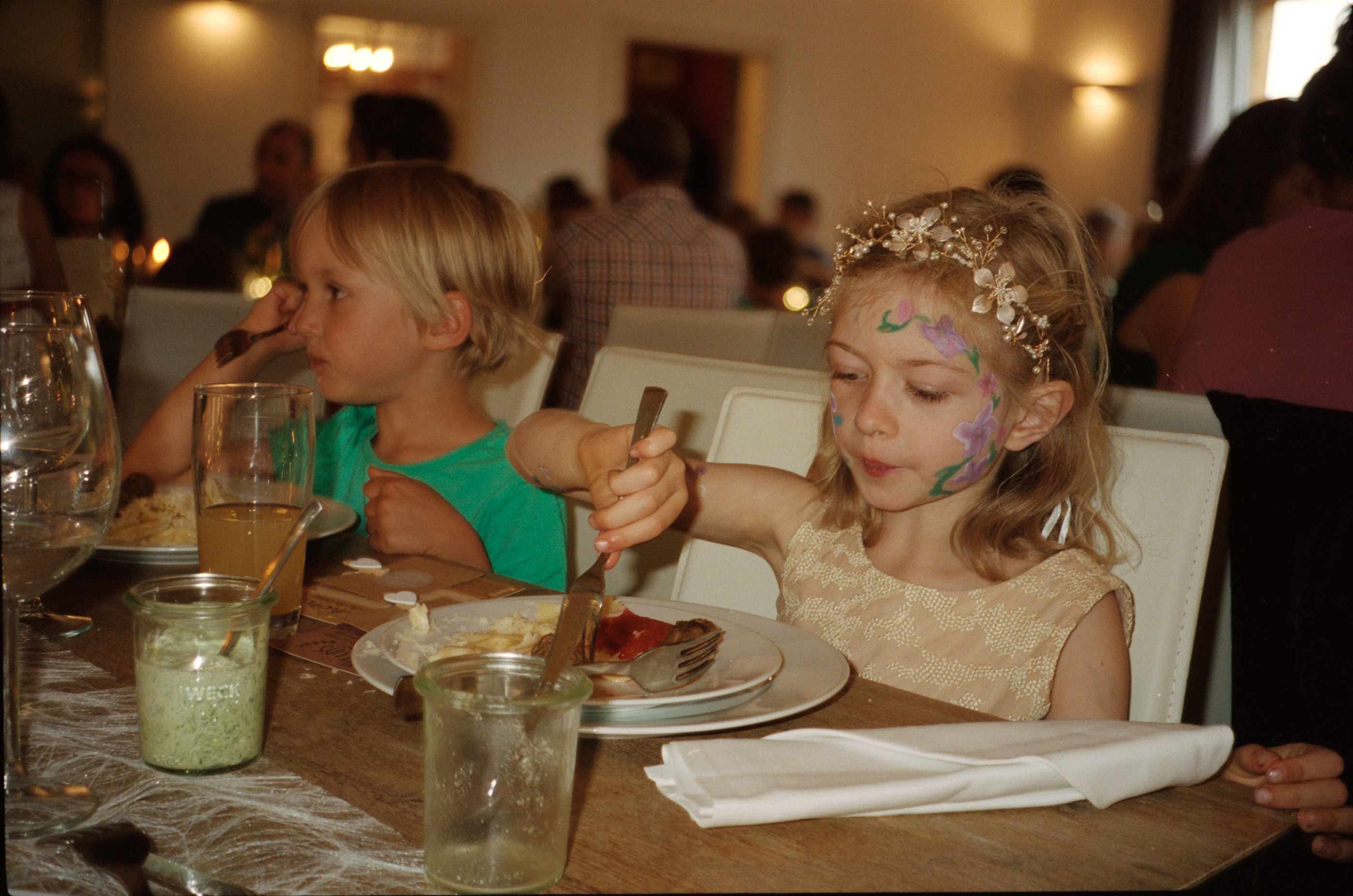 A young guest with painted face at the dinner table, Linda & Thomas wedding in Berlin