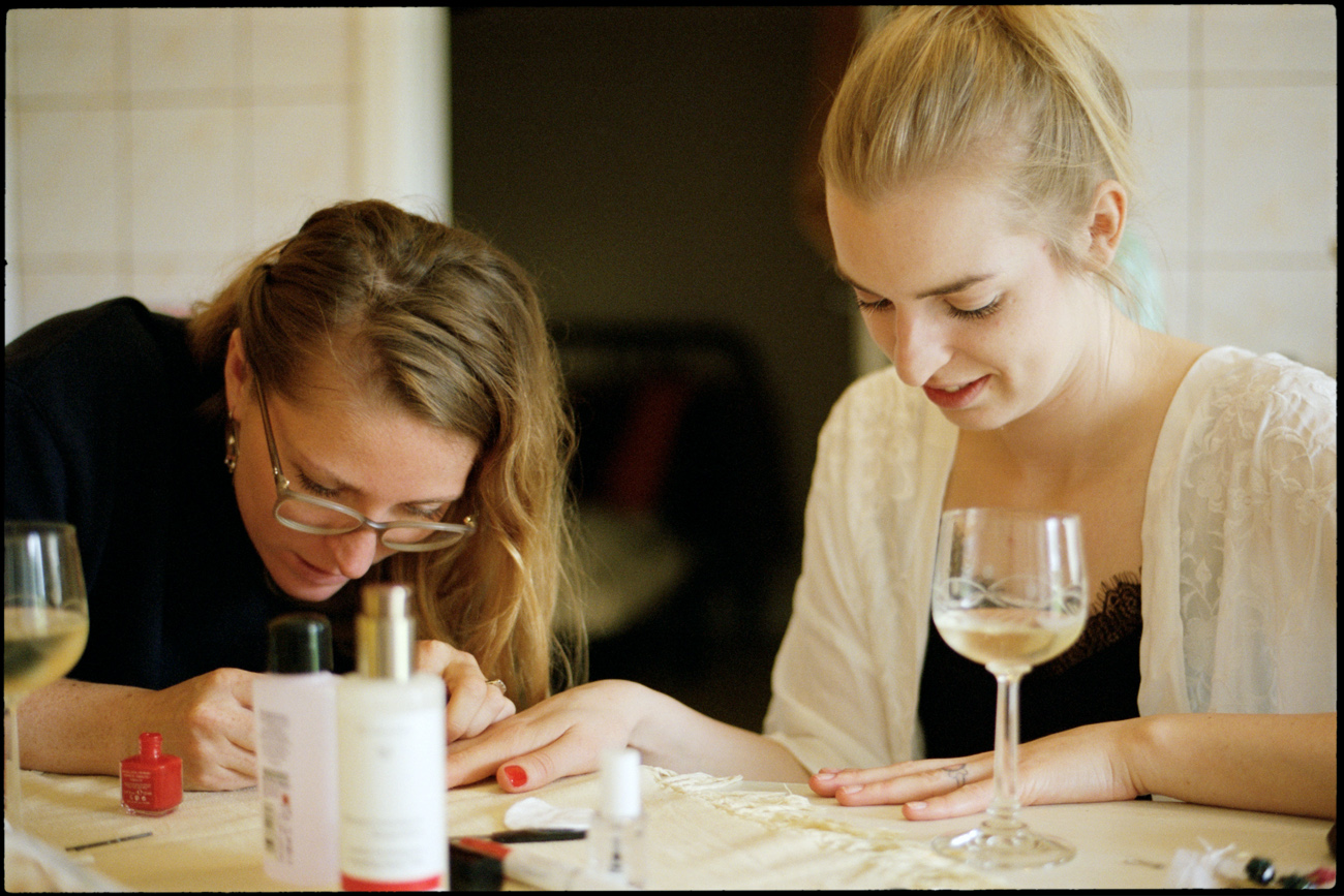 The bride and a guest getting ready together at a table, Maike & Daniel wedding in Brandenburg