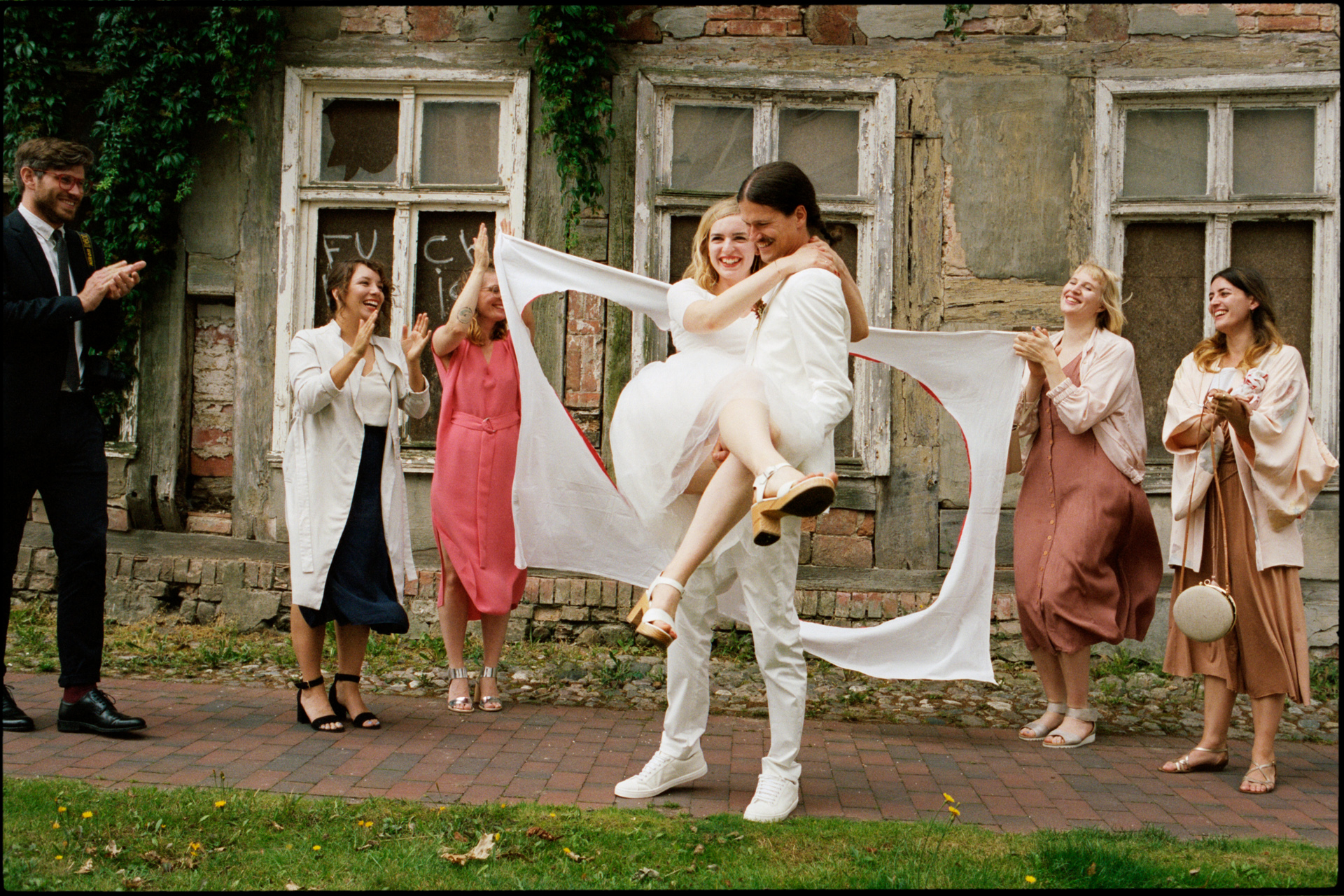 A wedding game, carrying the bride through a heart cut from a sheet, Maike & Daniel wedding in Brandenburg