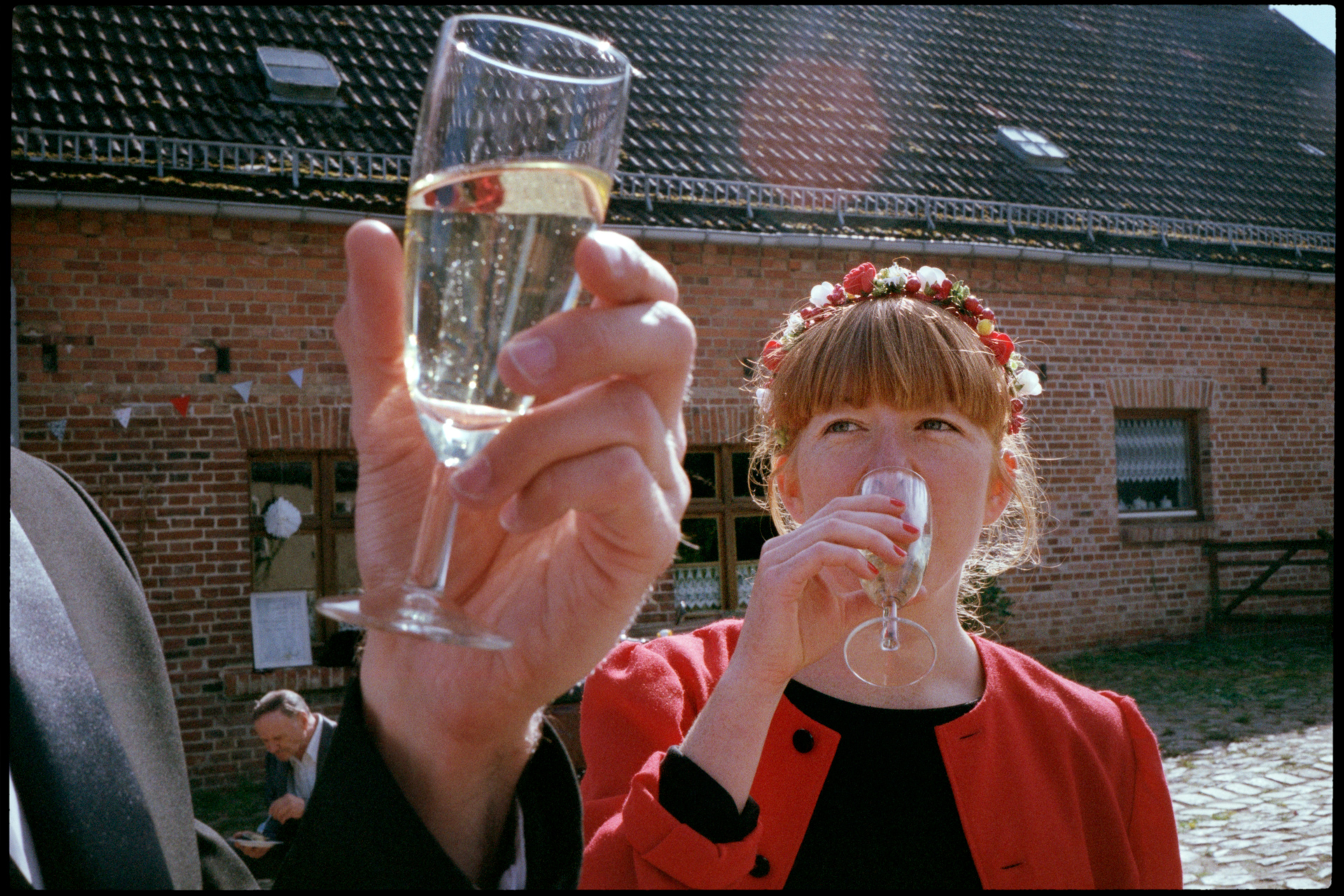 A guest raising a glass of sparkling wine, Maike & Daniel wedding in Brandenburg
