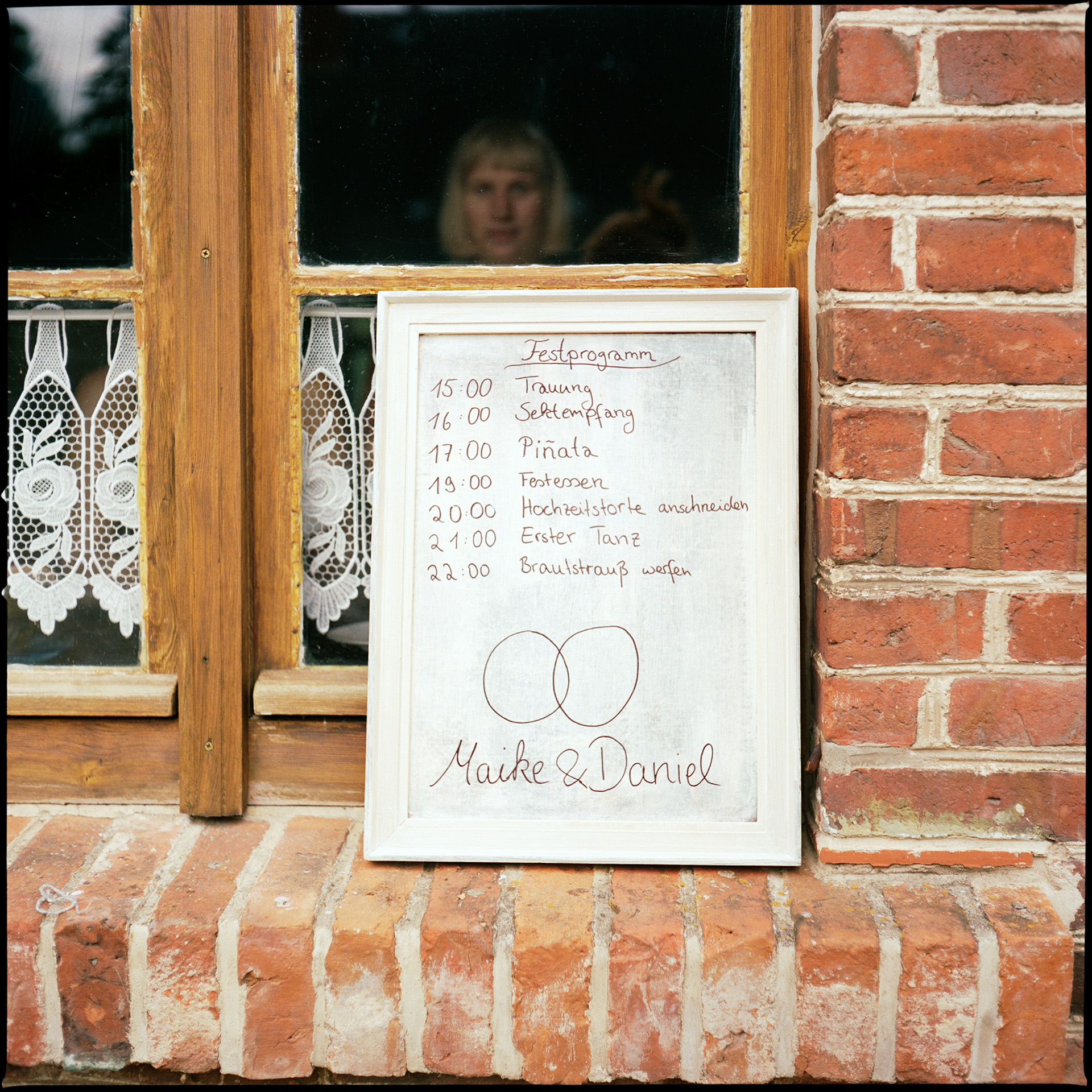 A handwritten schedule board for Maike and Daniel in a window, Maike & Daniel wedding in Brandenburg