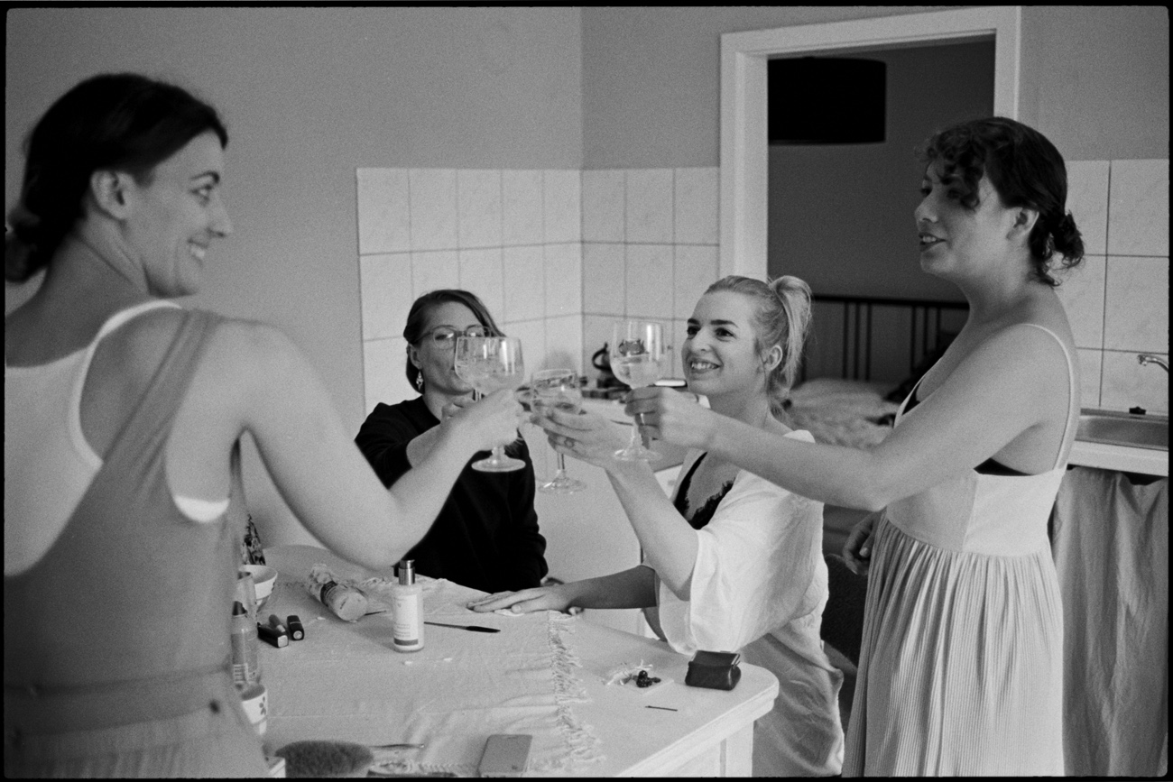 Friends toasting with drinks while getting ready, in black and white, Maike & Daniel wedding in Brandenburg