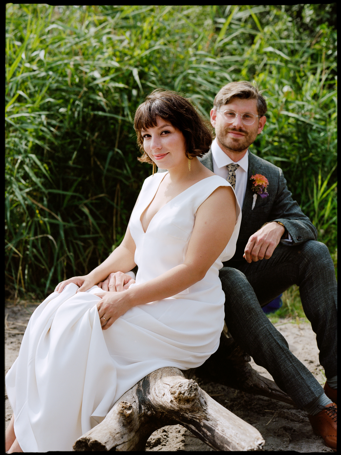 The couple sitting together by the reeds at the lakeshore, Suelyn & Pascal wedding in Groß Glienicke, Potsdam