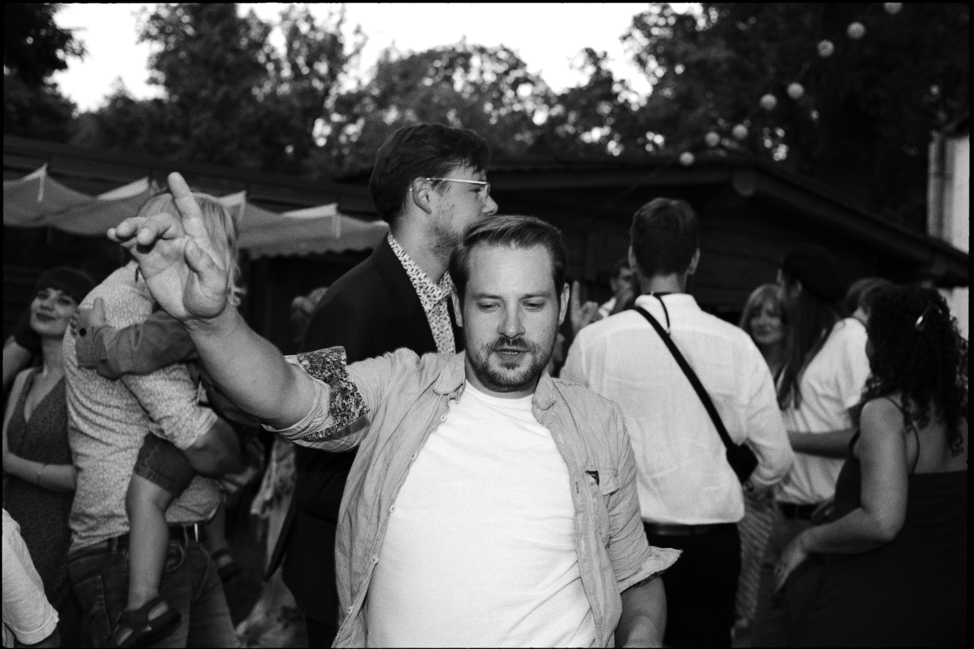 The groom among guests at the party, in black and white, Suelyn & Pascal wedding in Groß Glienicke, Potsdam