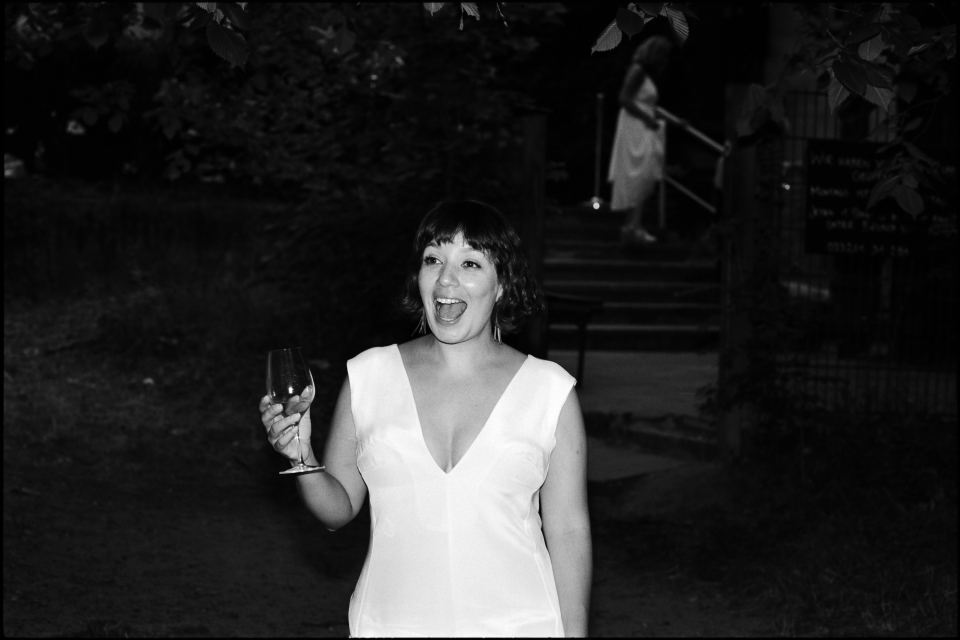 The bride laughing with a glass of wine, in black and white, Suelyn & Pascal wedding in Groß Glienicke, Potsdam
