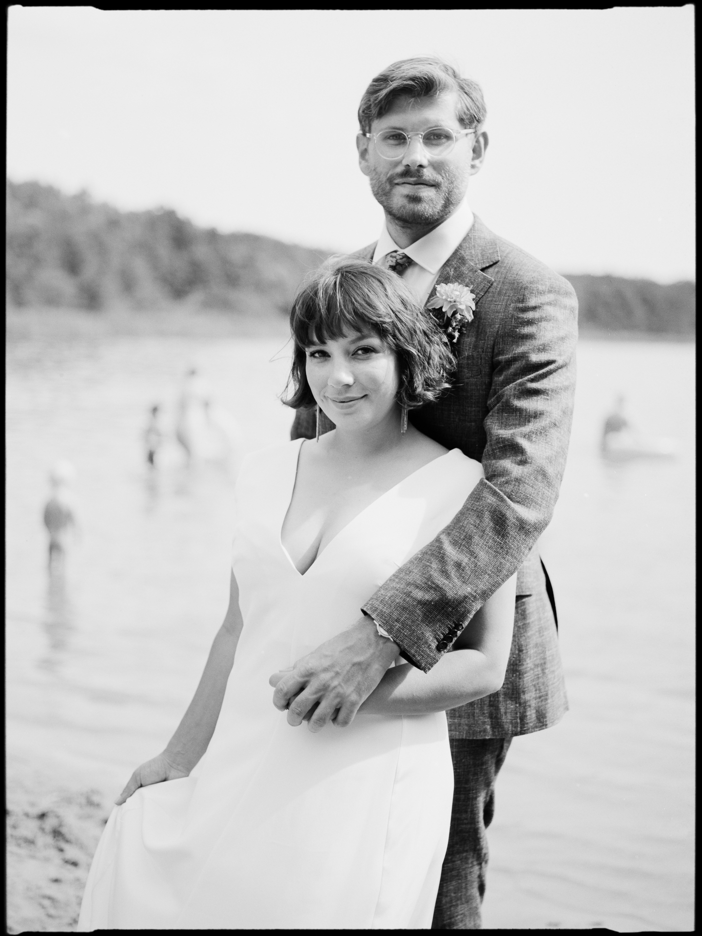 Portrait of the couple by the lake, swimmers behind, in black and white, Suelyn & Pascal wedding in Groß Glienicke, Potsdam