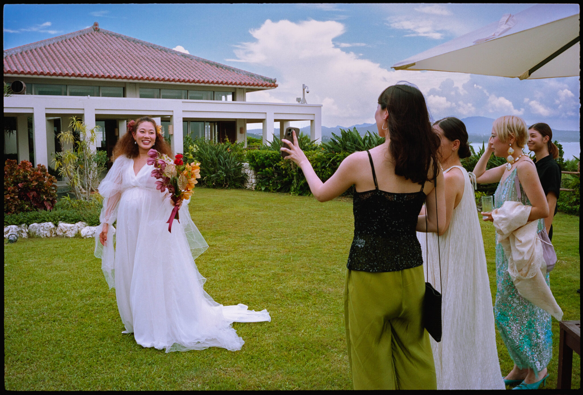 A guest photographing the bride on the lawn, Sugano & Jonas wedding in Okinawa