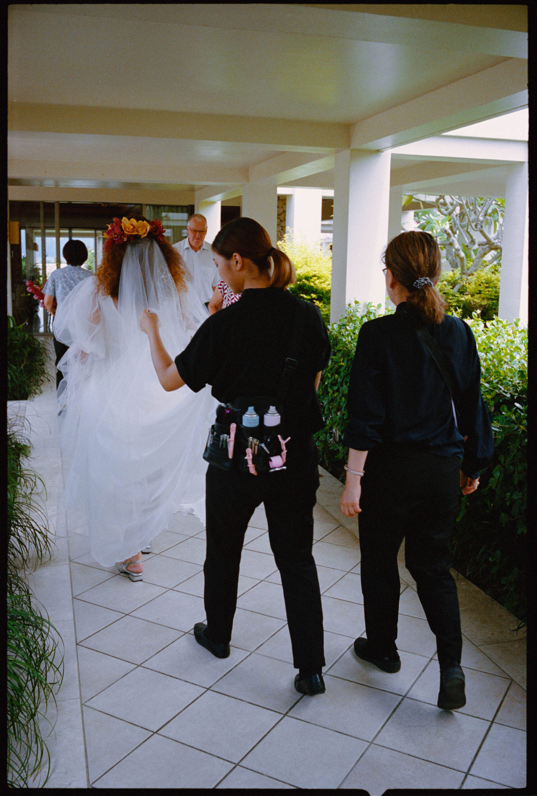 The bride walking with attendants along a walkway, Sugano & Jonas wedding in Okinawa