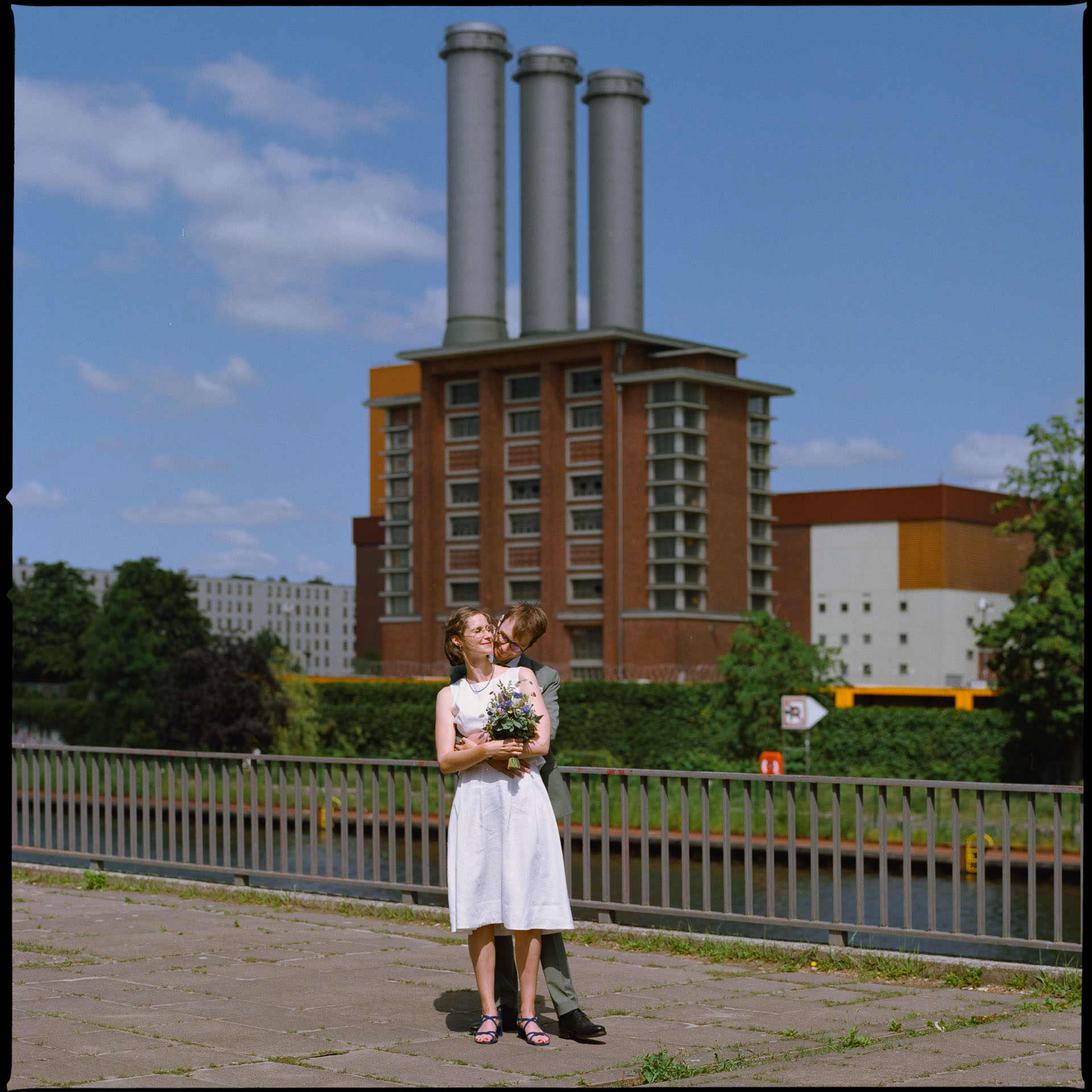Newlyweds standing on a bridge in front of a Berlin power station, 35mm film photograph