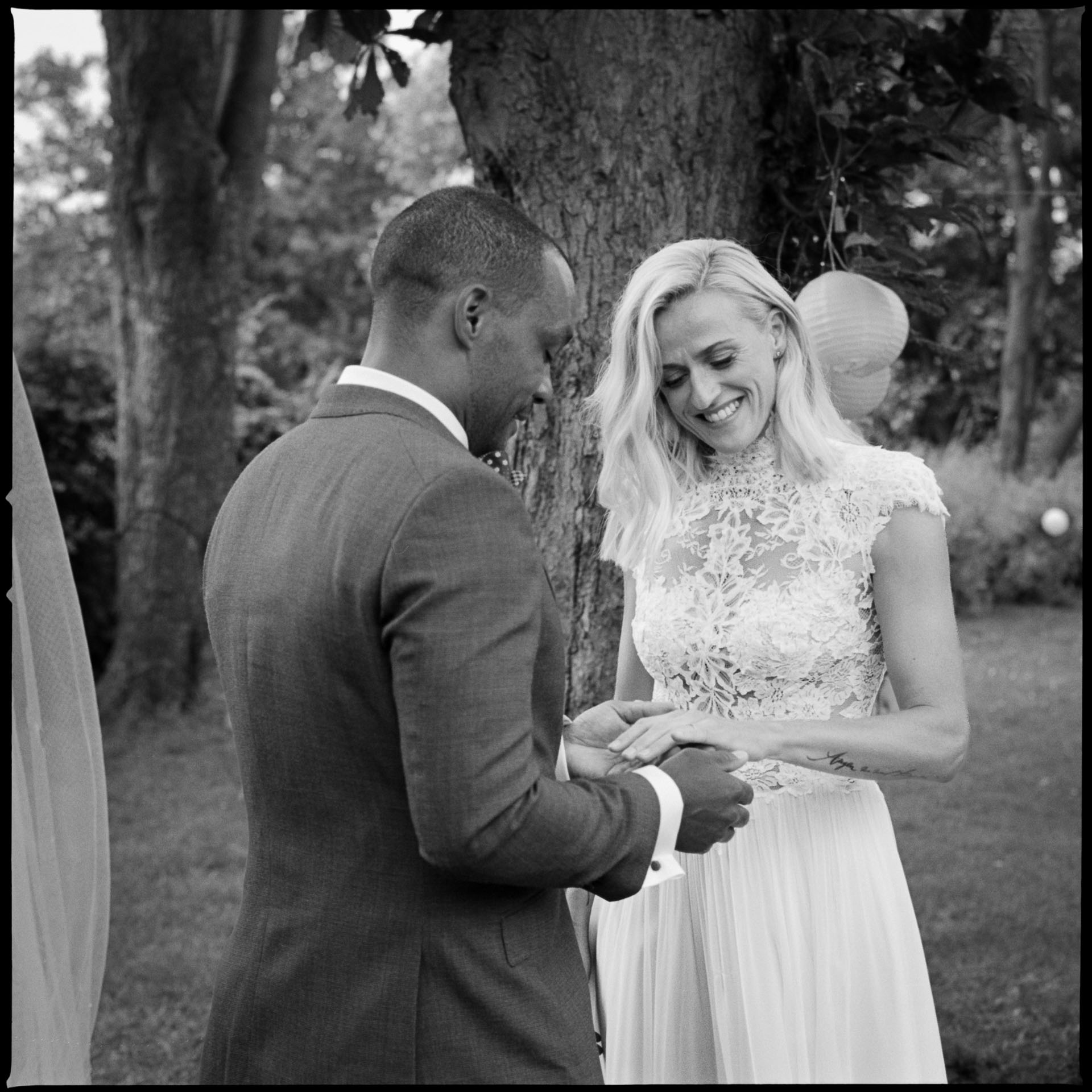 Bride and groom exchanging rings under a tree, black and white film photograph