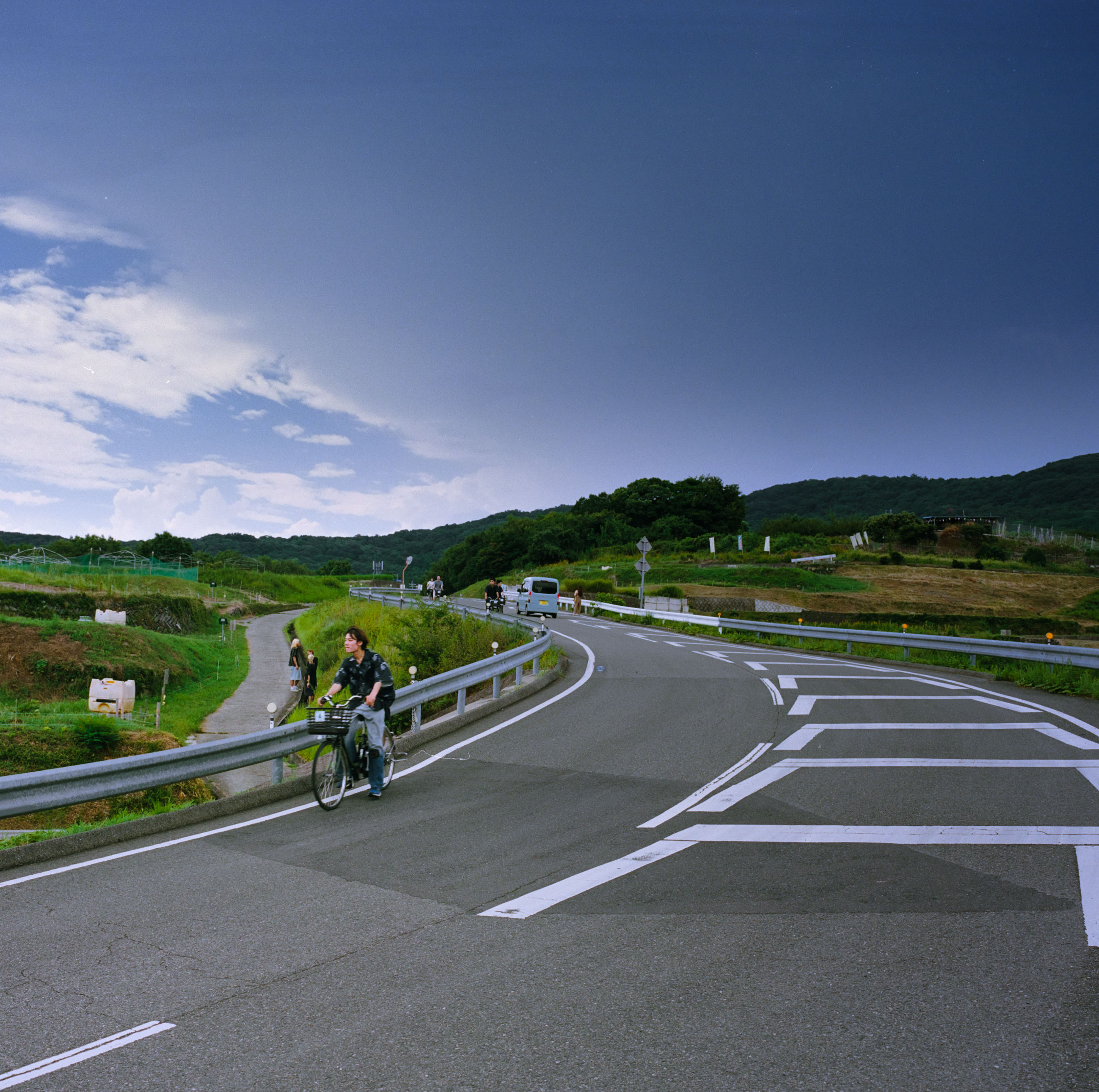 Young man on a bicycle rounding a guardrail curve on a country road