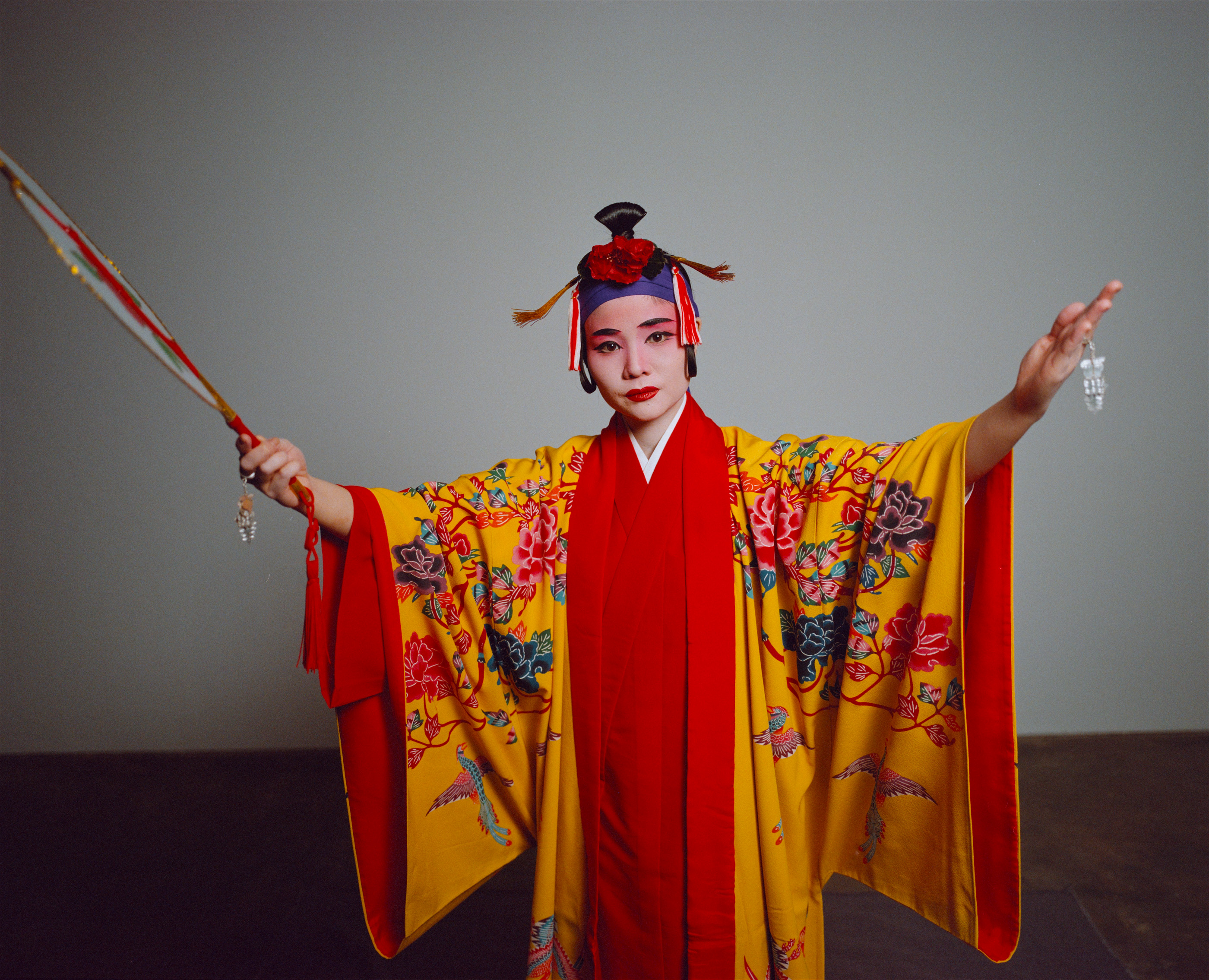 A dancer with arms outstretched in a yellow and red kimono, analogue film portrait by Martina Manz, Berlin