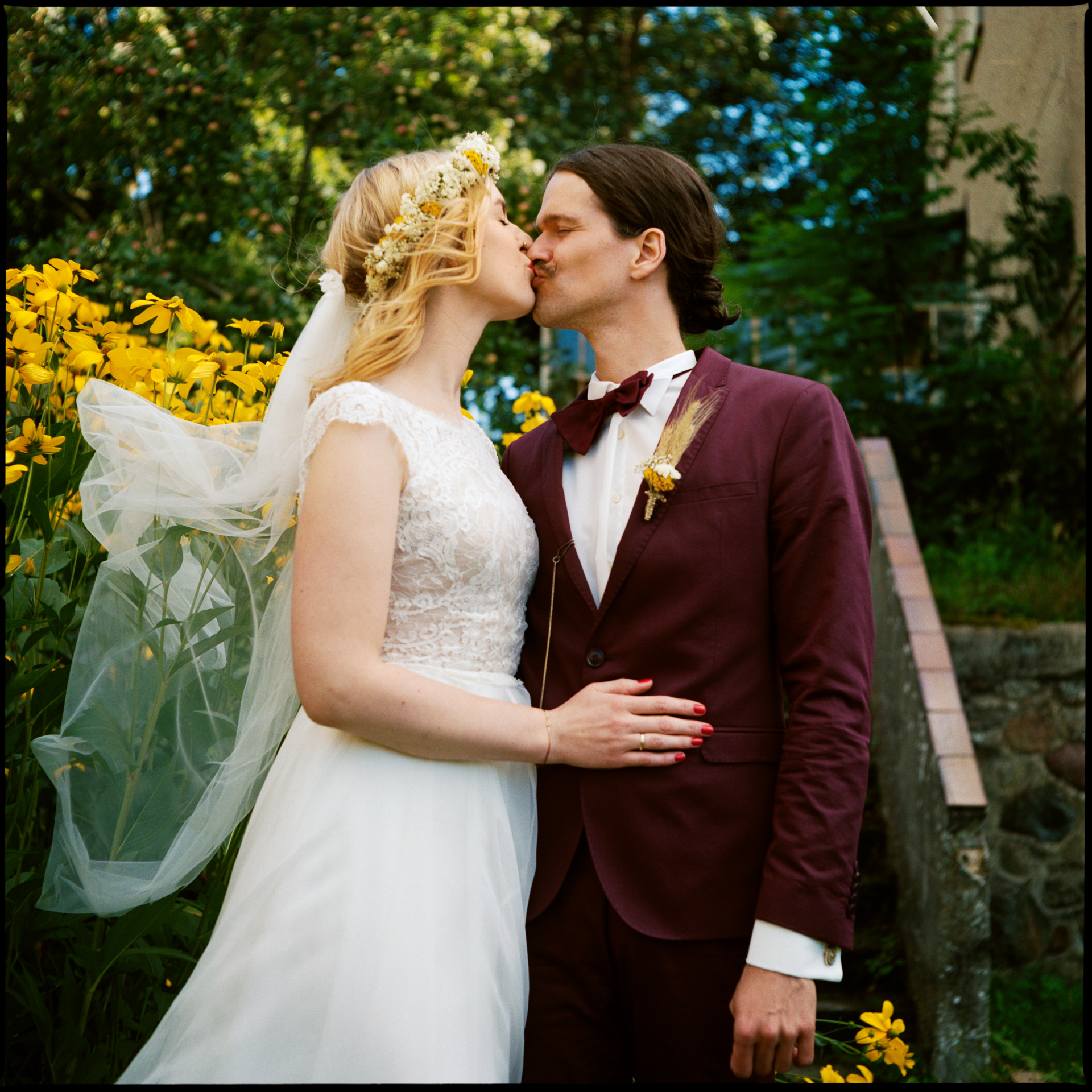 The couple kissing among yellow flowers, Maike & Daniel wedding in Brandenburg, analogue film photograph by Martina Manz